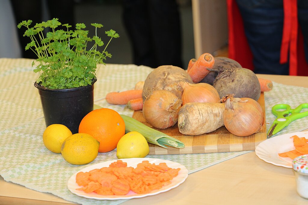 Gemüse und Obst Ein Topf mit Petersielie und verschiedenes Gemüse und Obst auf einem Tisch