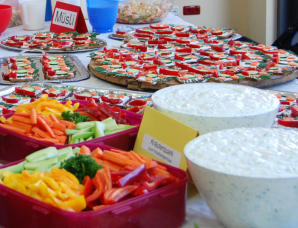 Gesundes Frühstück Auf einen Tisch stehen mehreren Schüsseln gefüllt mit Obst, Gemüse und Quark, Teller mit Brotgesichtern und weitere gesunde Leckereien