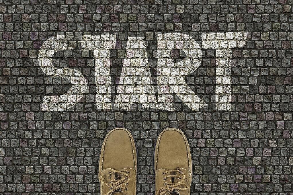 Foto: Füße, die vor dem geschriebenen Wort Start stehen